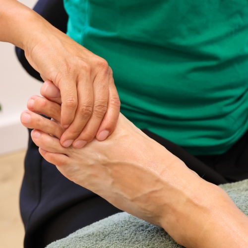 Zoneterapeut arbejder med tryk på fødderne under zoneterapi – naturlig behandling for krop og sind.